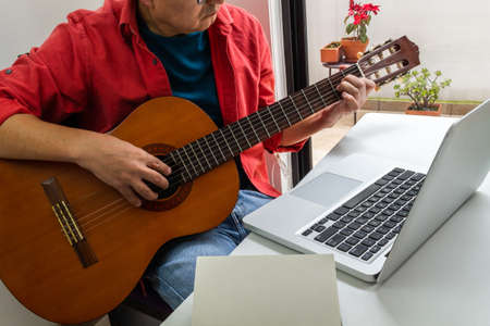 Man with glasses in electric guitar classes on the internet. Activities during quarantineの写真素材