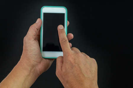 Hands using a cell phone on black background with path
