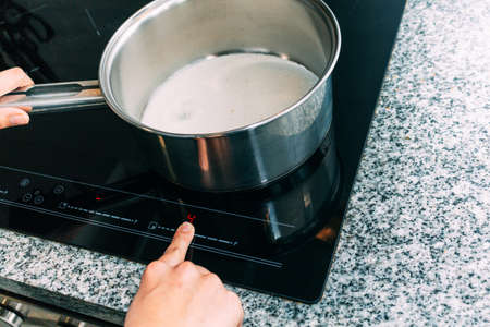 Female hand turns on electric hob closeup. Process to cook an apple cakeの写真素材
