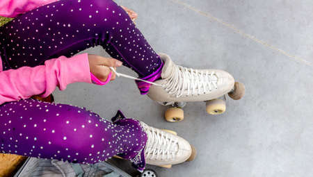 Legs of a skater who ties the laces of her roller skates. She's in a figure skating gloss suitの写真素材