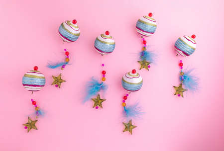 Colorful Christmas balls decorated with feathers, beads and stars on a pink background. Christmas decorationの写真素材