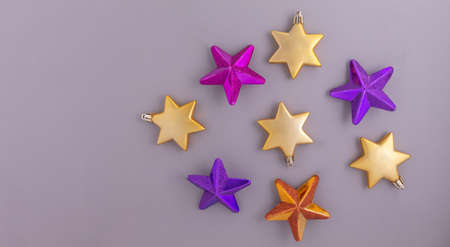 Colorful Christmas stars on a gray background. Banner of decorative elements. Gold, purple and pink decorationsの写真素材