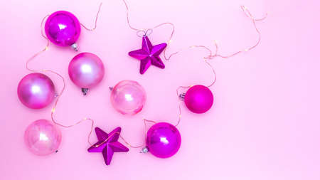 Aerial shot of balls and Christmas stars with small lights on a pink background. Top View