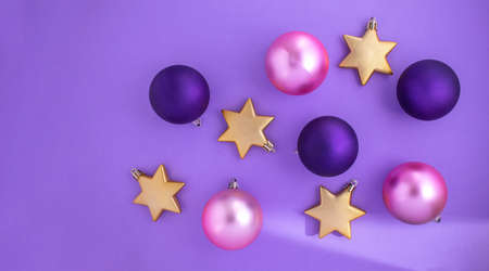 Pink and purple Christmas balls with gold stars on a purple background. Modern banner for Christmas...