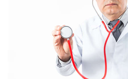 Doctor in a white coat whose face is not recognized with a stethoscope in his hands in action of listening to the heart or lungs for a medical examination in a hospitalの写真素材