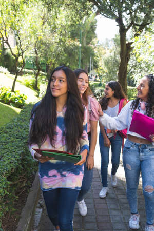 Selective focus of a teenage girl walking towards school while her friends come behind in a parkの写真素材