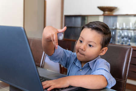 Four year old boy interacting with a laptop at homeの写真素材