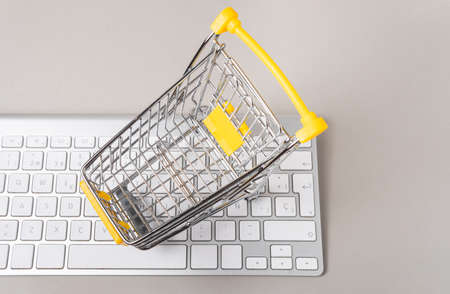 Overhead view of a miniature shopping cart on a computer keyboardの写真素材