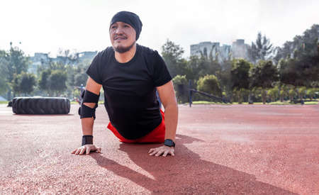 Latin man doing cobra stretch and exercising in a park. Concept of exercises and yoga