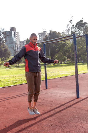 Brazilian bald man jumping rope exercising in a park