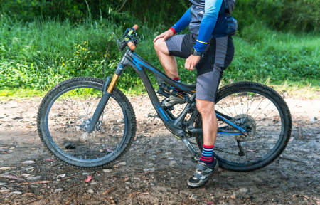 Detail of an unrecognizable man on a mountain bike on a trail.