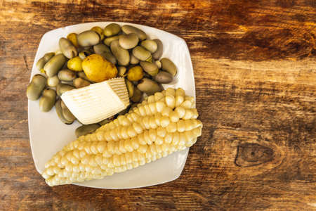 Corn plate with broad beans and fresh cheese on a rustic wooden table. Traditional food from the...