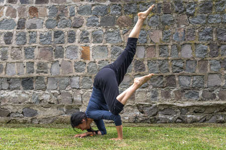 Woman in her 40s practicing yoga in flying crow pose outdoors in the morning
