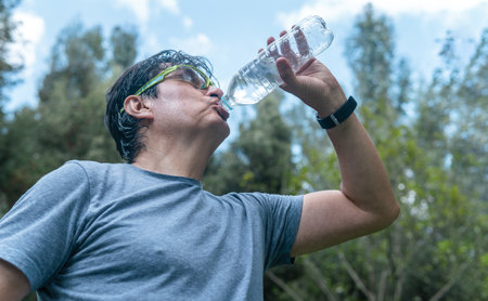 Latino man drinking water in a forest in a training