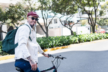 Smiling man looking at camera making a stop on his bike ride in the cityの写真素材