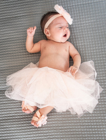 latina babe lying on a bed yawning in a pink ballet dressの写真素材