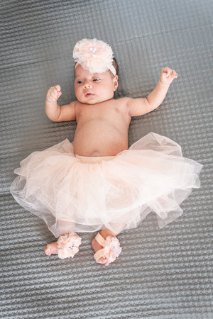 baby girl in tutu and pink ballet slippers lying on a gray blanketの写真素材