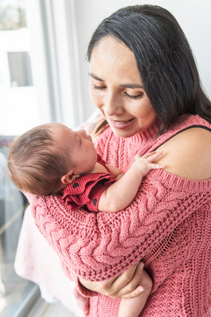 Mother looking at her baby tenderly as she carries her in her armsの写真素材