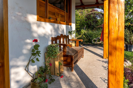 Porch in front of a country house with wooden bench in the middle of the vegetationの写真素材