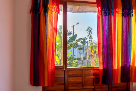 Window overlooking a garden and colorful curtainsの写真素材