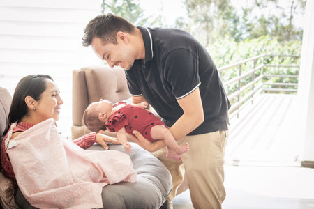Father of a baby delivering his daughter in the arms of her mother who is preparing to breastfeed herの写真素材