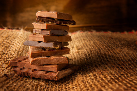Column of chocolate pieces on a rustic background with copy space on a jute baseの写真素材