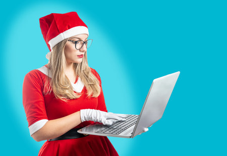 Young mom noel with serious glasses working on laptop isolated on light blue backgroundの写真素材