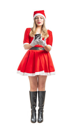 Young latin Santa Claus woman looking at a message on her cell phone isolated on white backgroundの写真素材