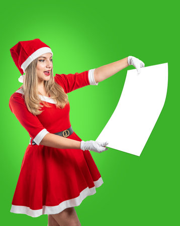 Latina Santa Claus woman showing a poster with copy space on green background at Christmasの写真素材