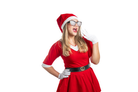 Excited woman dressed as Santa Claus with sunglasses makes happy gestures on Christmas isolated on white backgroundの写真素材