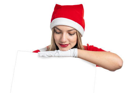Young blonde woman Mama Noel looks attentively at a poster with copy space that she holds in her hands for a Christmas messageの写真素材