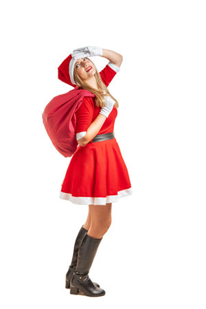 Young blonde woman dressed as Santa Claus walks making gestures and expressions with a bag of gifts at Christmasの写真素材