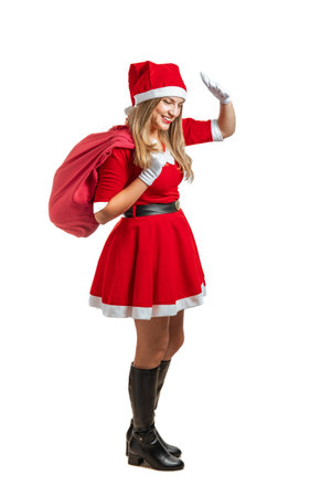 Young latin woman Santa Claus walking smiling with a red gift bag at Christmasの写真素材