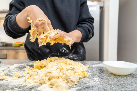 Hands of a young woman wiping off the dough that is stuck to her while preparing a pastry recipeの写真素材