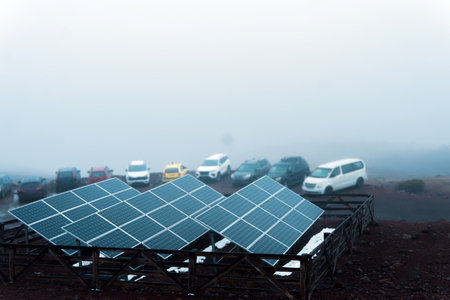 Solar panels generating clean energy in a foggy mountain parking lot, promoting sustainable transportation and renewable powerの写真素材