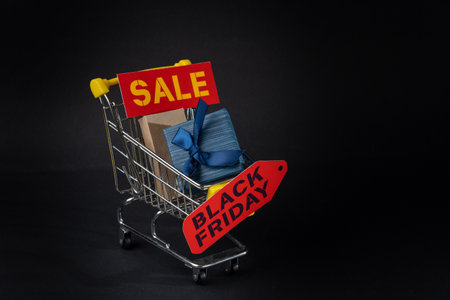 Shopping cart carrying gifts and black friday sale tags, promoting seasonal discounts and shopping dealsの写真素材