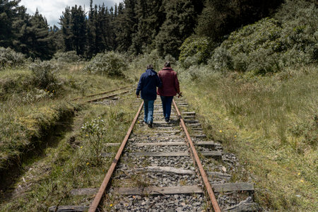 Two people are walking along abandoned railway tracks, embodying journey and togethernessの写真素材