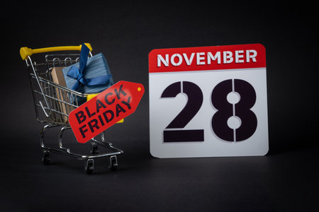 Miniature shopping cart with black friday tag and november 28th calendar symbolizing upcoming sales and dealsの写真素材