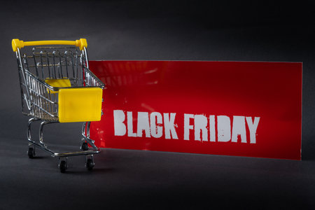 Miniature shopping cart next to a red black friday sign, symbolizing sales and consumerism during the biggest shopping event of the yearの写真素材