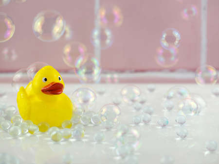 Yellow rubber duck in bathroom with bubbles and pink tilesの写真素材