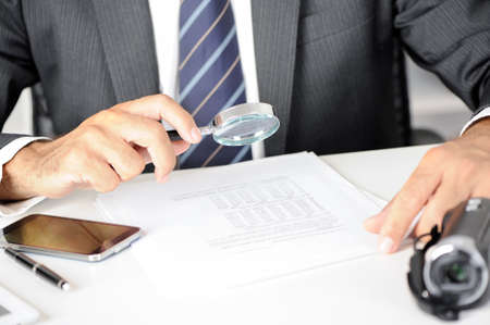 Businessman checking a document with a magnifying glass