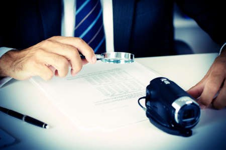 Businessman looking through a magnifying glass to documentsの写真素材