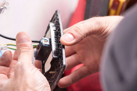 The hands of an electrician installing a power socketの写真素材