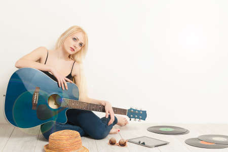 Girl musician sitting on a floor with acoustic guitarの写真素材