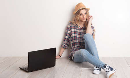 Casual young lady sitting on a wooden floor at homeの写真素材