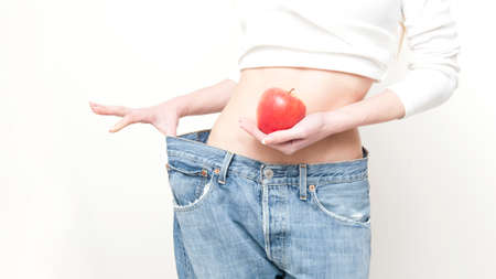Slim girl in big jeans isolated on whiteの写真素材