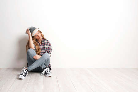 girl sits in a depression on the floor near the wallの写真素材
