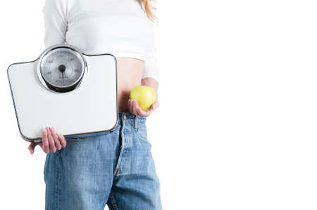 Young girl holding a scale and a fresh apple, healthy eating, fitness and weight loss conceptの写真素材