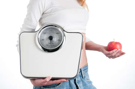 Young girl holding a scale and a fresh apple, healthy eating, fitness and weight loss concept