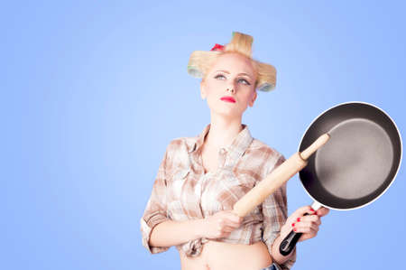 housewife with a rolling pin and a pan on blue backgroundの写真素材